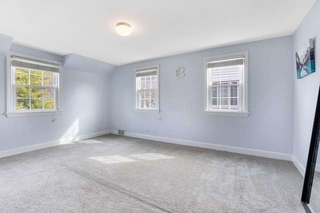 empty room with carpet floors, visible vents, and baseboards