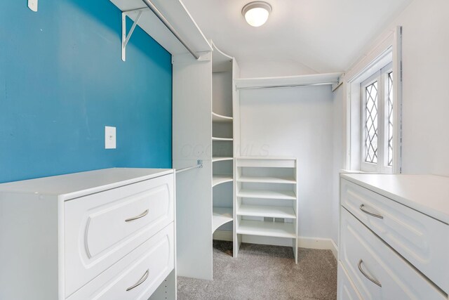 walk in closet with light carpet and lofted ceiling