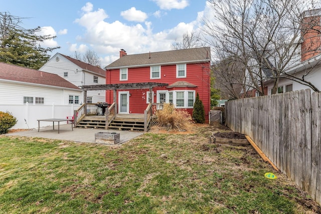 rear view of property with a wooden deck, a patio, a fenced backyard, a chimney, and a yard