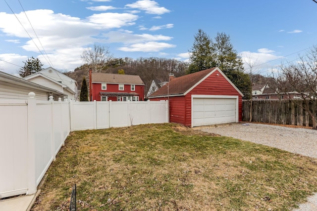 view of yard featuring a garage, a fenced backyard, and an outdoor structure