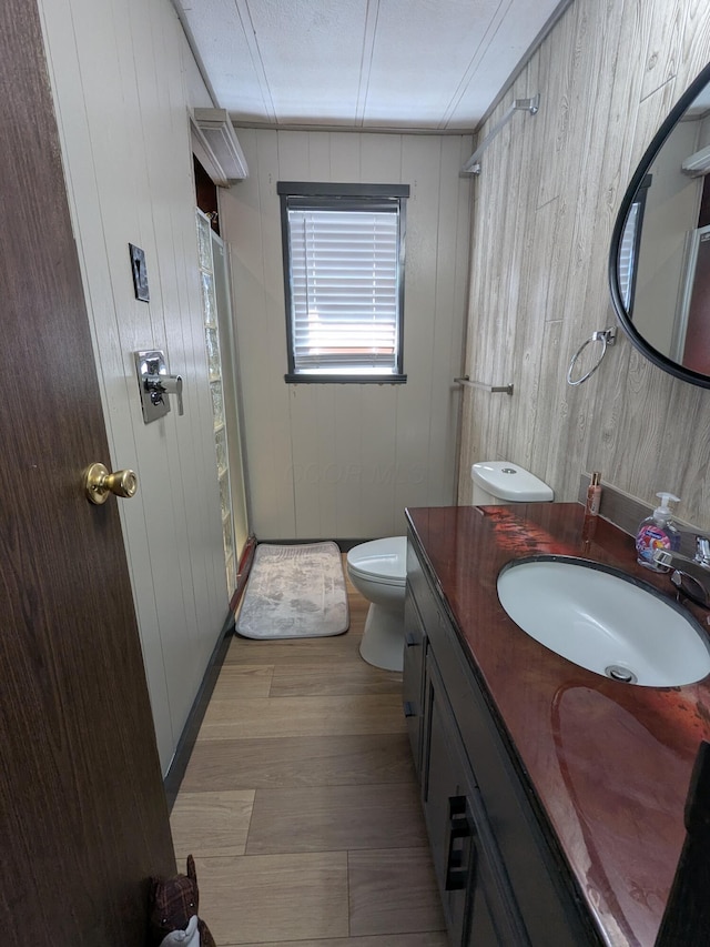 bathroom featuring a shower, vanity, toilet, and wood finished floors