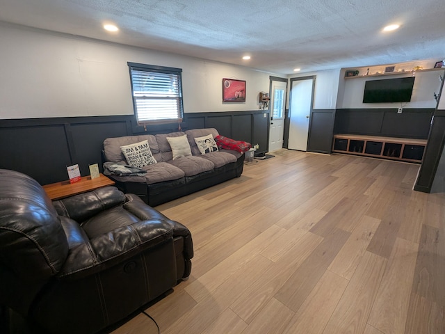 living area featuring a wainscoted wall, light wood finished floors, recessed lighting, a decorative wall, and a textured ceiling