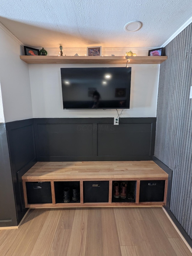 unfurnished living room with wainscoting, a textured ceiling, and wood finished floors