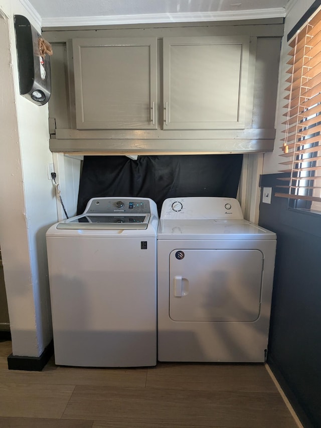 laundry area featuring separate washer and dryer, wood finished floors, and cabinet space