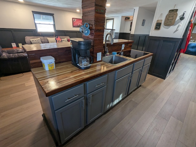 kitchen with a wainscoted wall, a sink, and wooden counters