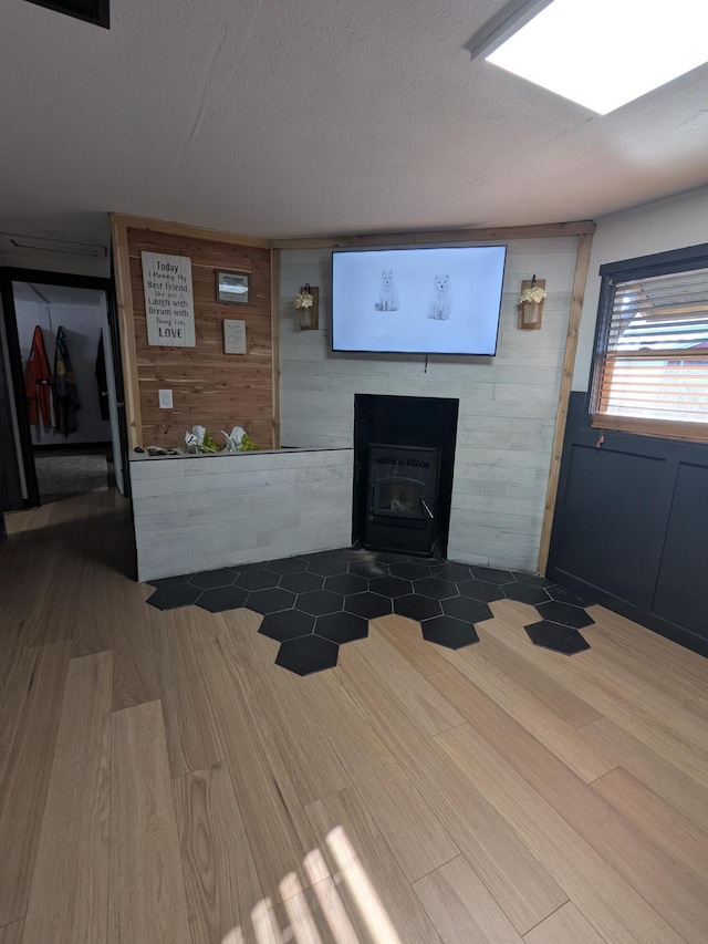 unfurnished living room featuring wooden walls, a textured ceiling, and wood finished floors