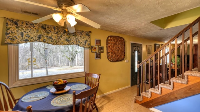 dining room with visible vents, a textured ceiling, light tile patterned floors, baseboards, and stairs