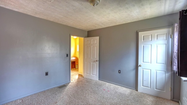 unfurnished bedroom with a textured ceiling, baseboards, and carpet floors