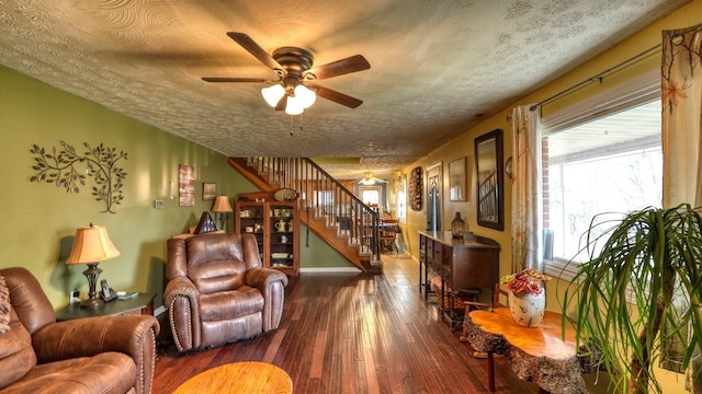 living room with stairway, dark wood-type flooring, a ceiling fan, and a textured ceiling