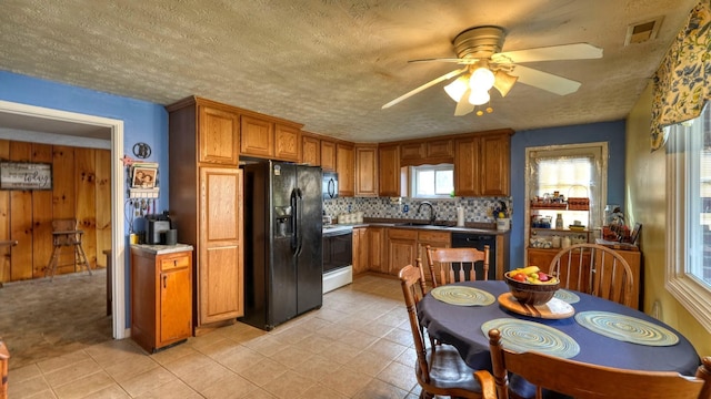 kitchen with visible vents, backsplash, brown cabinetry, black appliances, and a sink