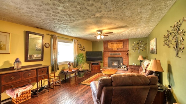 living room with a textured ceiling, a wood stove, ceiling fan, and hardwood / wood-style floors