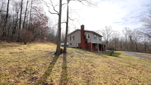 view of property exterior featuring a yard, brick siding, and a chimney