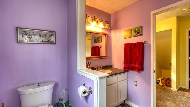 bathroom with toilet, vanity, and baseboards