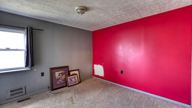 carpeted empty room with visible vents, a textured ceiling, and baseboards