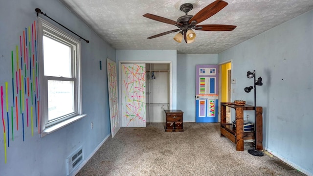 carpeted bedroom featuring visible vents, a ceiling fan, a textured ceiling, a closet, and baseboards