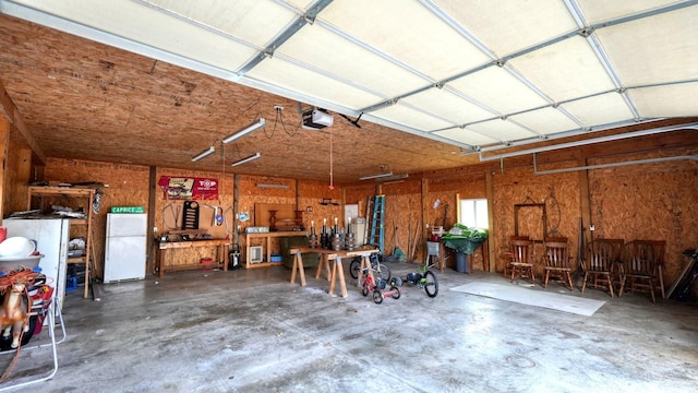 garage with a workshop area, a garage door opener, and freestanding refrigerator