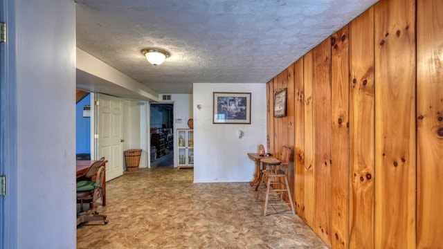 home office with visible vents, wood walls, and a textured ceiling