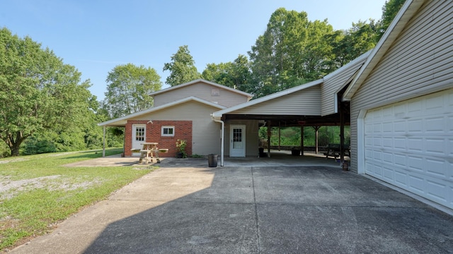 225 Homestead Dr, New Concord, OH 43762 - view of front of house featuring a front yard, a carport, driveway, a garage, and brick siding