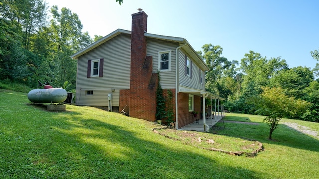225 Homestead Dr, New Concord, OH 43762 - view of home's exterior featuring a chimney, a lawn, and a patio area