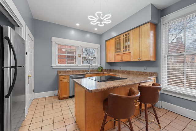 kitchen with light tile patterned floors, baseboards, a breakfast bar area, stainless steel appliances, and a sink