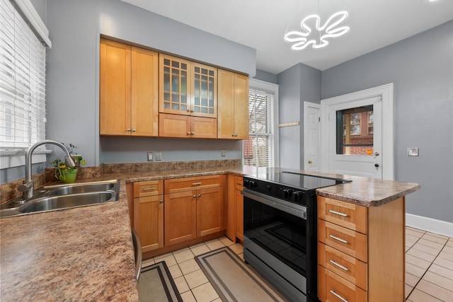 kitchen with range with electric cooktop, light tile patterned flooring, a sink, and a peninsula