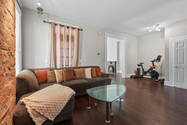 living area featuring baseboards, brick wall, and wood finished floors