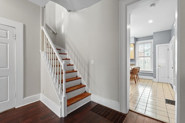 stairway with visible vents, baseboards, and wood finished floors