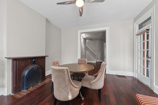 dining area featuring a fireplace with flush hearth, dark wood-style flooring, stairway, and baseboards