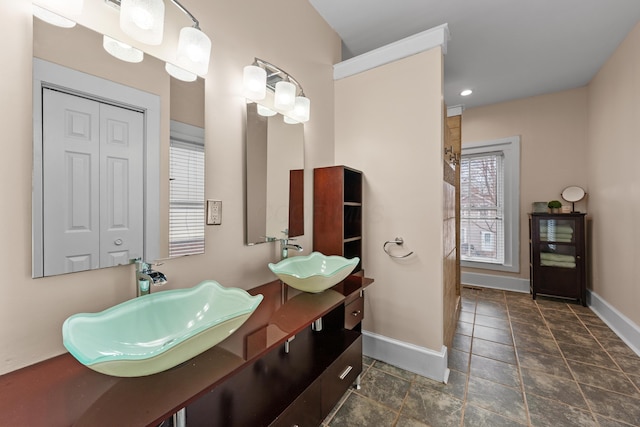 bathroom with double vanity, a sink, and baseboards