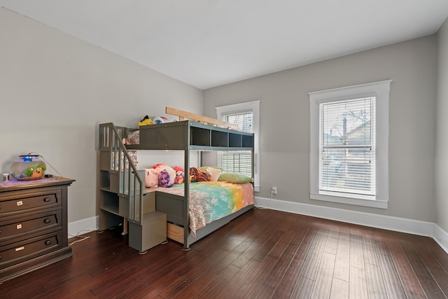 bedroom with multiple windows, baseboards, and wood finished floors