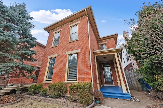 view of front of house featuring fence and brick siding