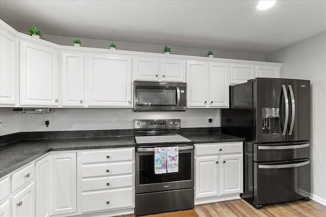 kitchen featuring white cabinets, dark countertops, stainless steel electric range, and black refrigerator with ice dispenser