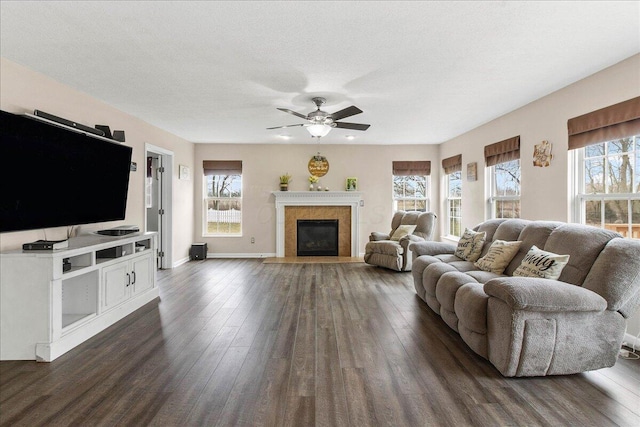 living area featuring a fireplace with flush hearth, baseboards, dark wood finished floors, and a textured ceiling