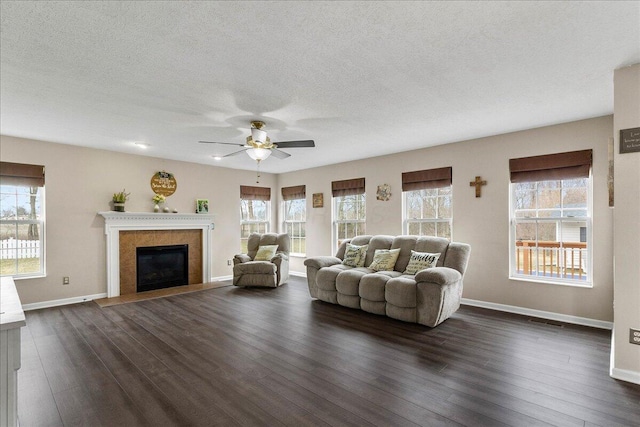 unfurnished living room featuring dark wood-style flooring, plenty of natural light, and a tile fireplace