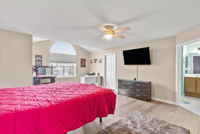 bedroom featuring ensuite bathroom, vaulted ceiling, a textured ceiling, wood finished floors, and baseboards