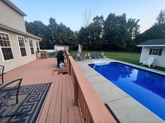 outdoor pool featuring a deck, an outdoor structure, a yard, a shed, and a patio area