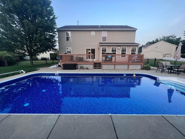 outdoor pool with a patio area, fence, and a wooden deck