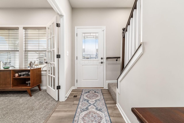 entryway featuring light wood-style flooring, stairway, baseboards, and french doors