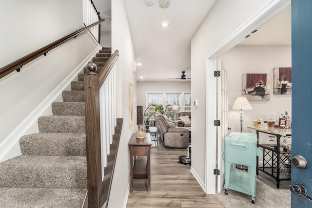 stairway featuring baseboards, a ceiling fan, wood finished floors, and recessed lighting