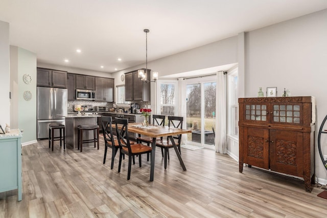 dining area featuring a chandelier, light wood-type flooring, baseboards, and recessed lighting