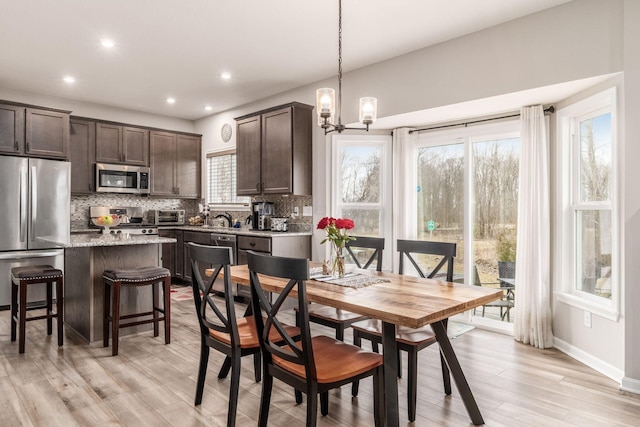 dining space featuring light wood-style flooring, a chandelier, baseboards, and recessed lighting