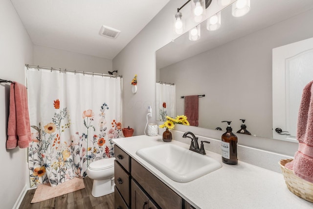 bathroom featuring toilet, a shower with shower curtain, wood finished floors, vanity, and visible vents