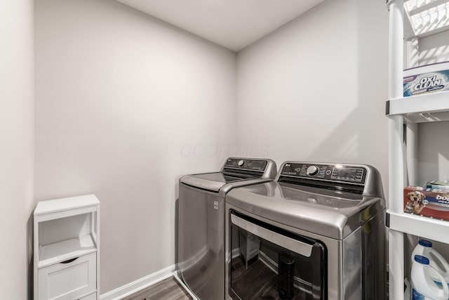 laundry area featuring baseboards, laundry area, wood finished floors, and washer and dryer