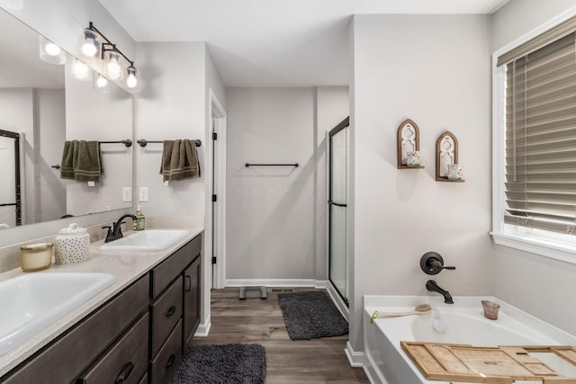 full bathroom with a stall shower, a garden tub, a sink, and wood finished floors