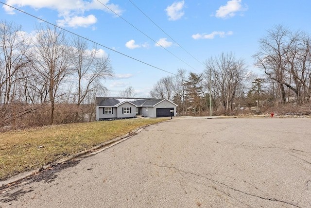 view of front of house featuring an attached garage, driveway, and a front lawn