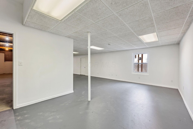 basement featuring a paneled ceiling and baseboards