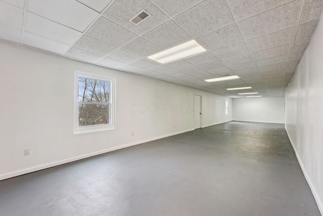 basement with a paneled ceiling, baseboards, and visible vents