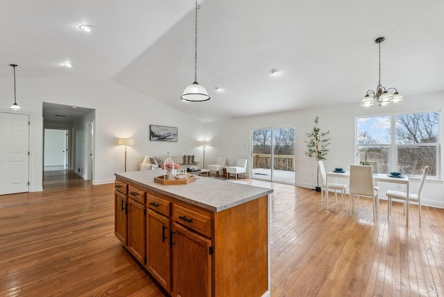 kitchen featuring a kitchen island, vaulted ceiling, hanging light fixtures, open floor plan, and hardwood / wood-style floors