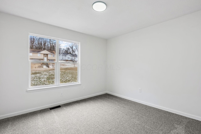 carpeted spare room with visible vents and baseboards