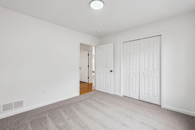 unfurnished bedroom with a closet, carpet, visible vents, and baseboards